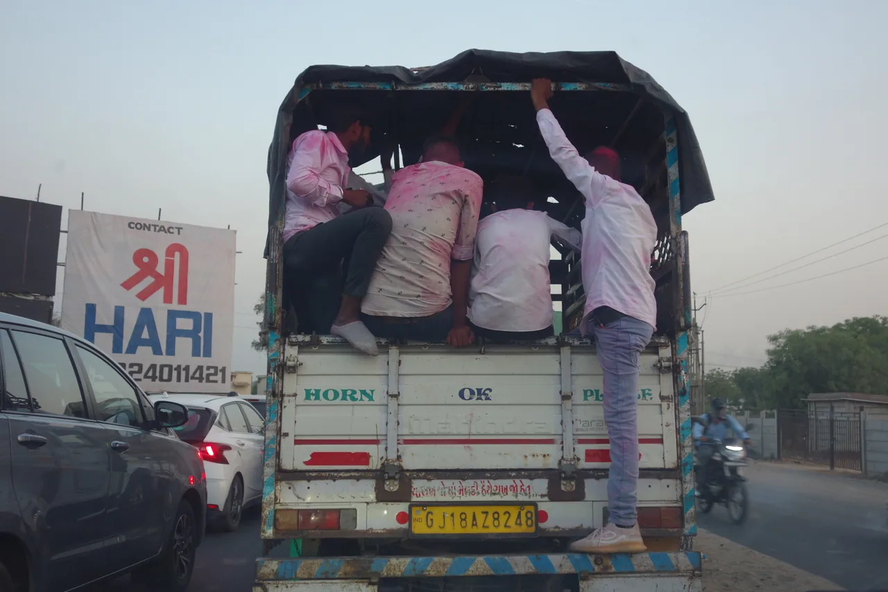 People riding in the open back of a goods vehicle