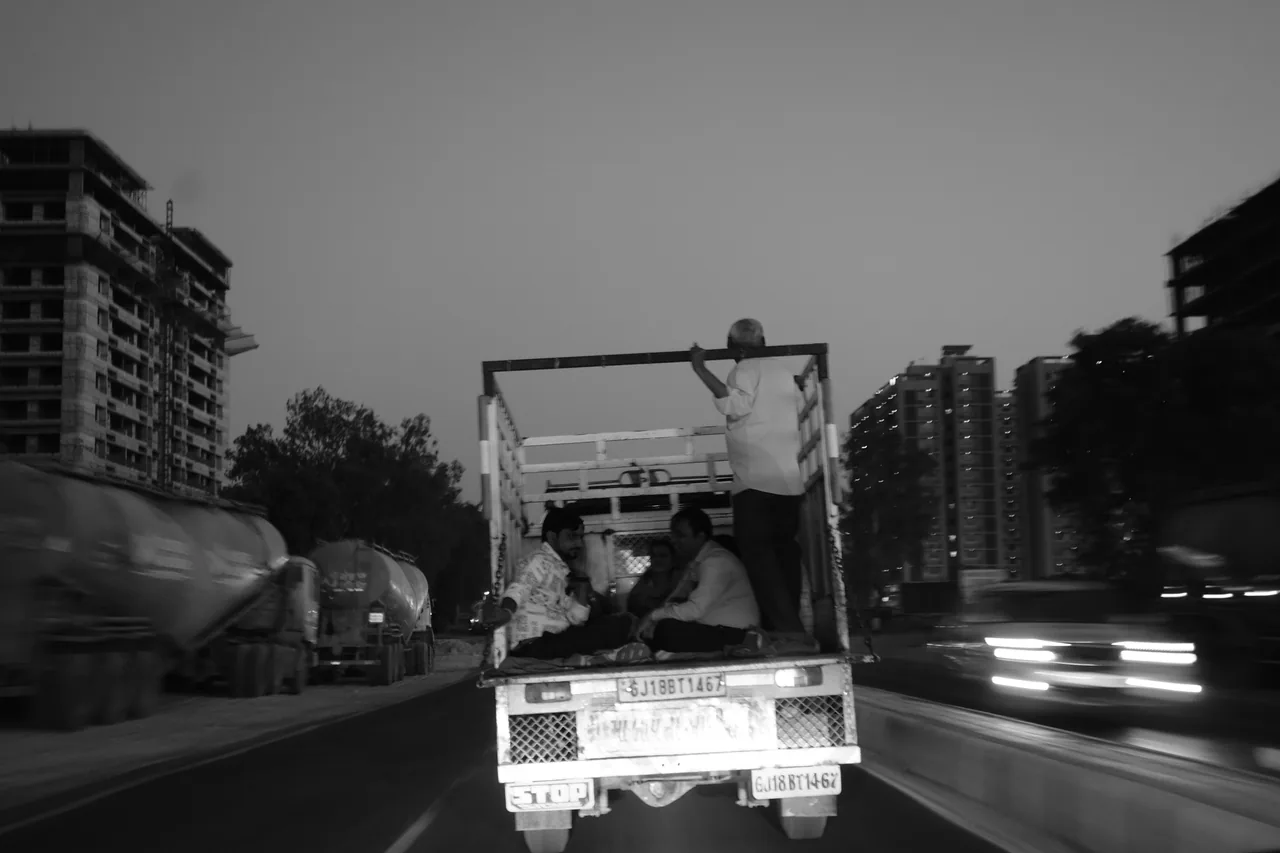 An open truck passing through city traffic, in black and white