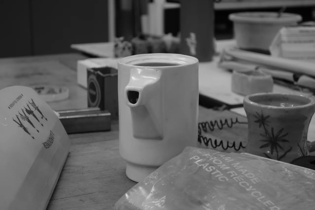Cups and small objects arranged on a table, in black and white