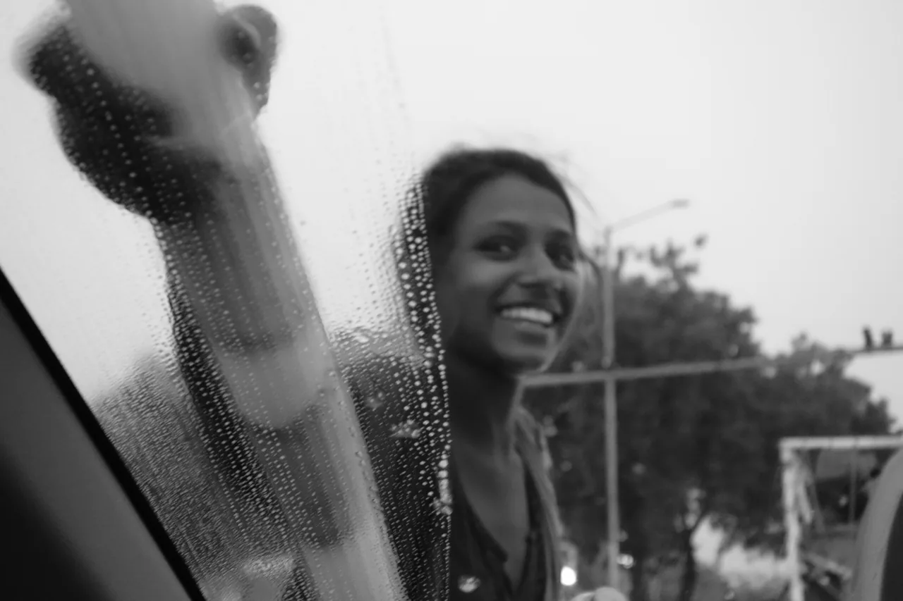 A smiling woman wiping a wet window