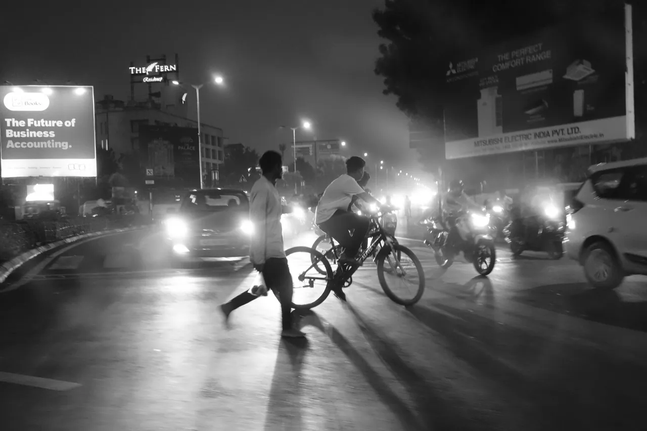 People and bicycles crossing a road amid headlights at night