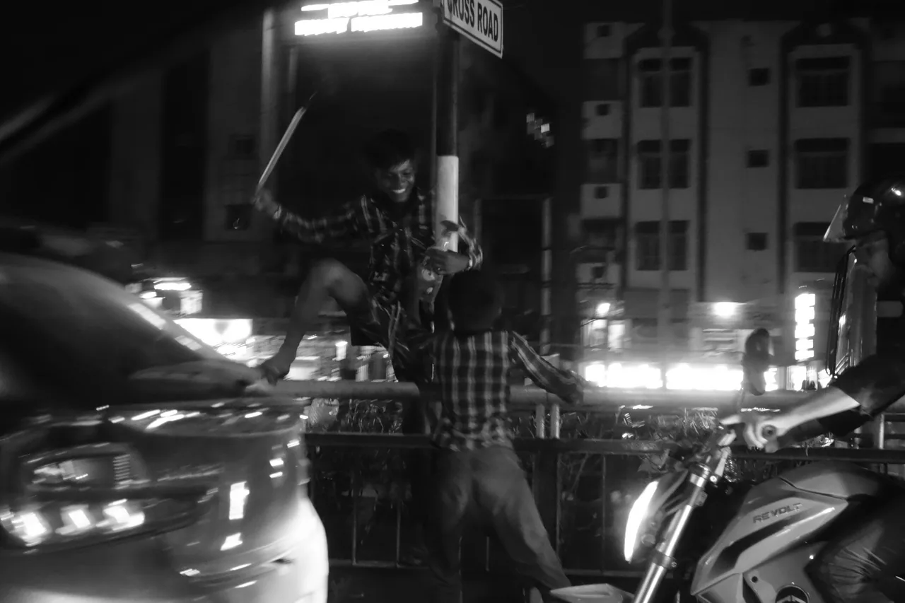 A street vendor among vehicles and bright lights at night