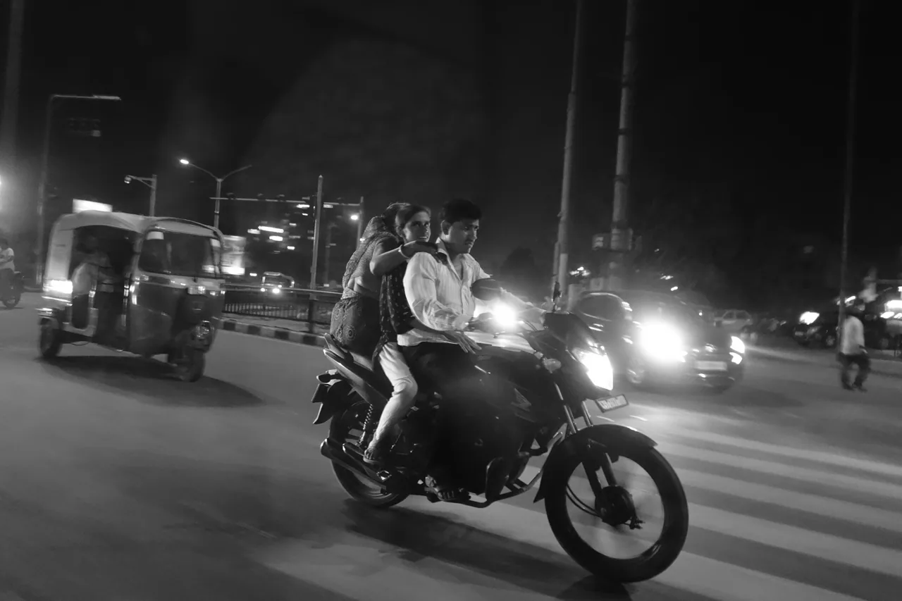 Motorcycle riders moving through a busy night-time street