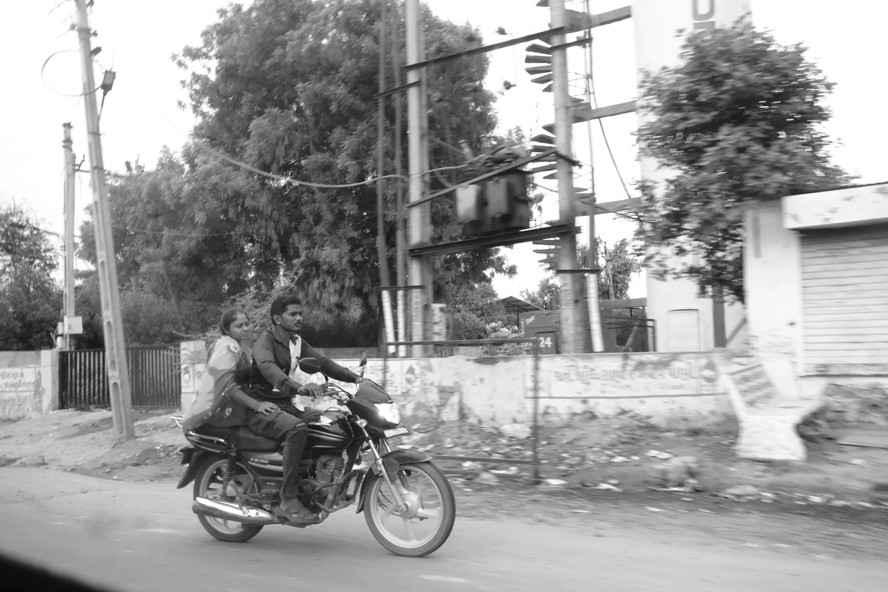 A motorcycle passing trees and an electrical transformer