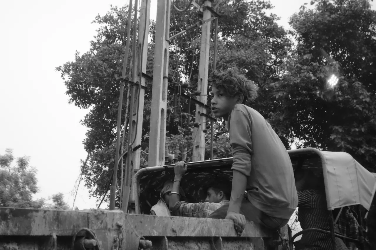 A man standing beside a roadside cart under trees