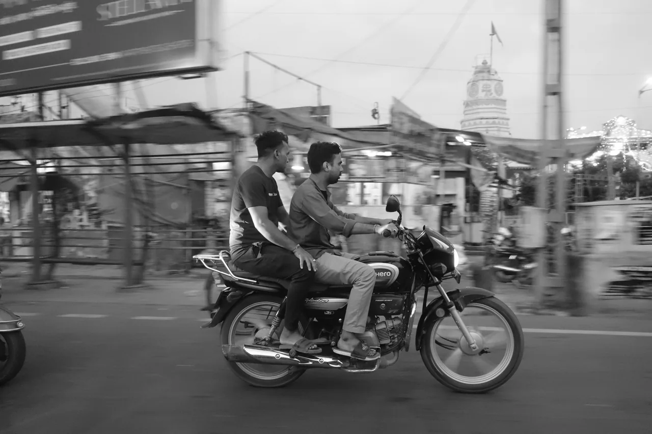 Motorcycle riders passing shops in the daytime