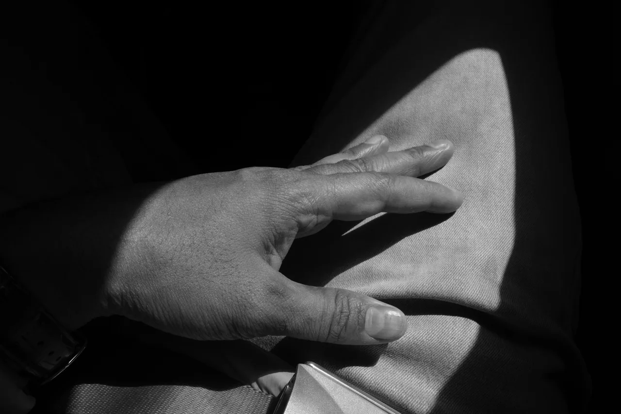 A hand resting on a knee in directional light