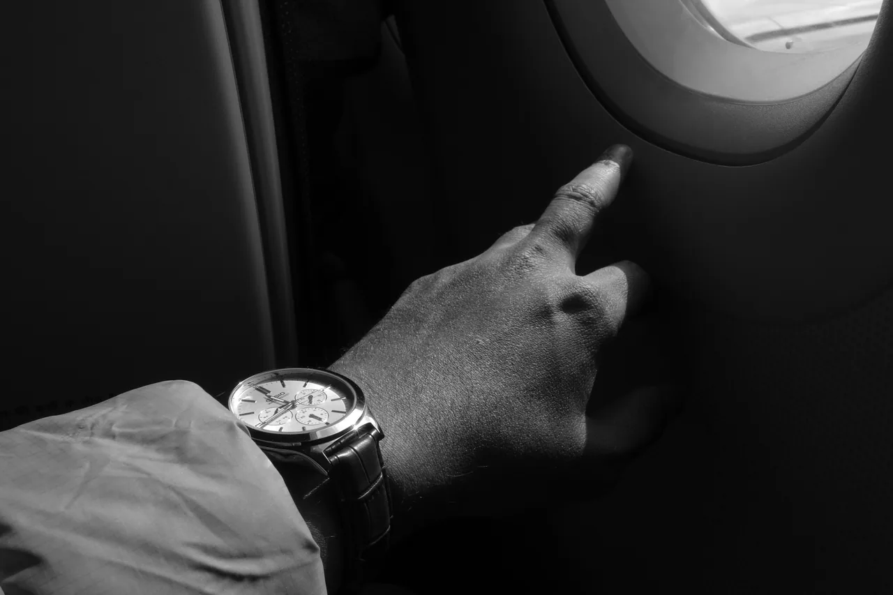 A wristwatch and a hand beside a small window