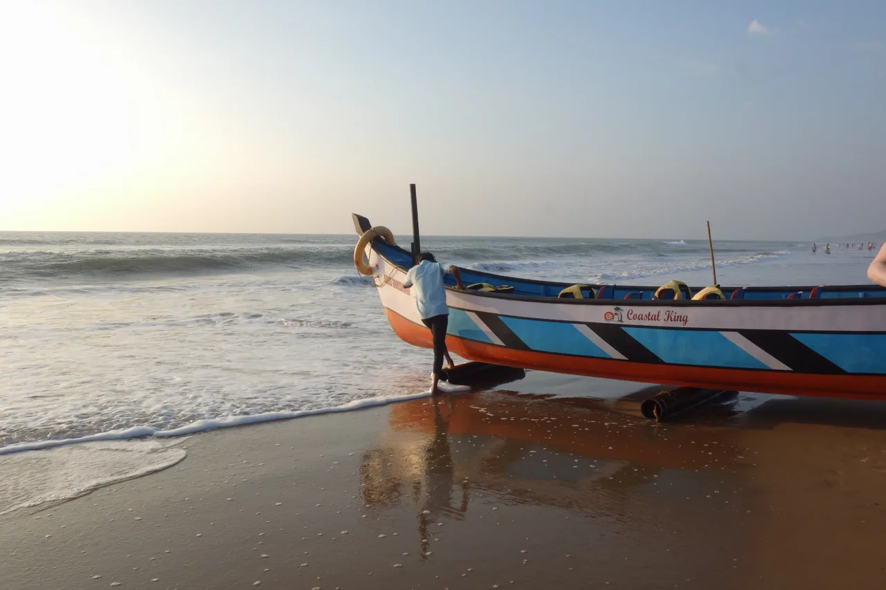 A colourful fishing boat on wet sand in soft evening light